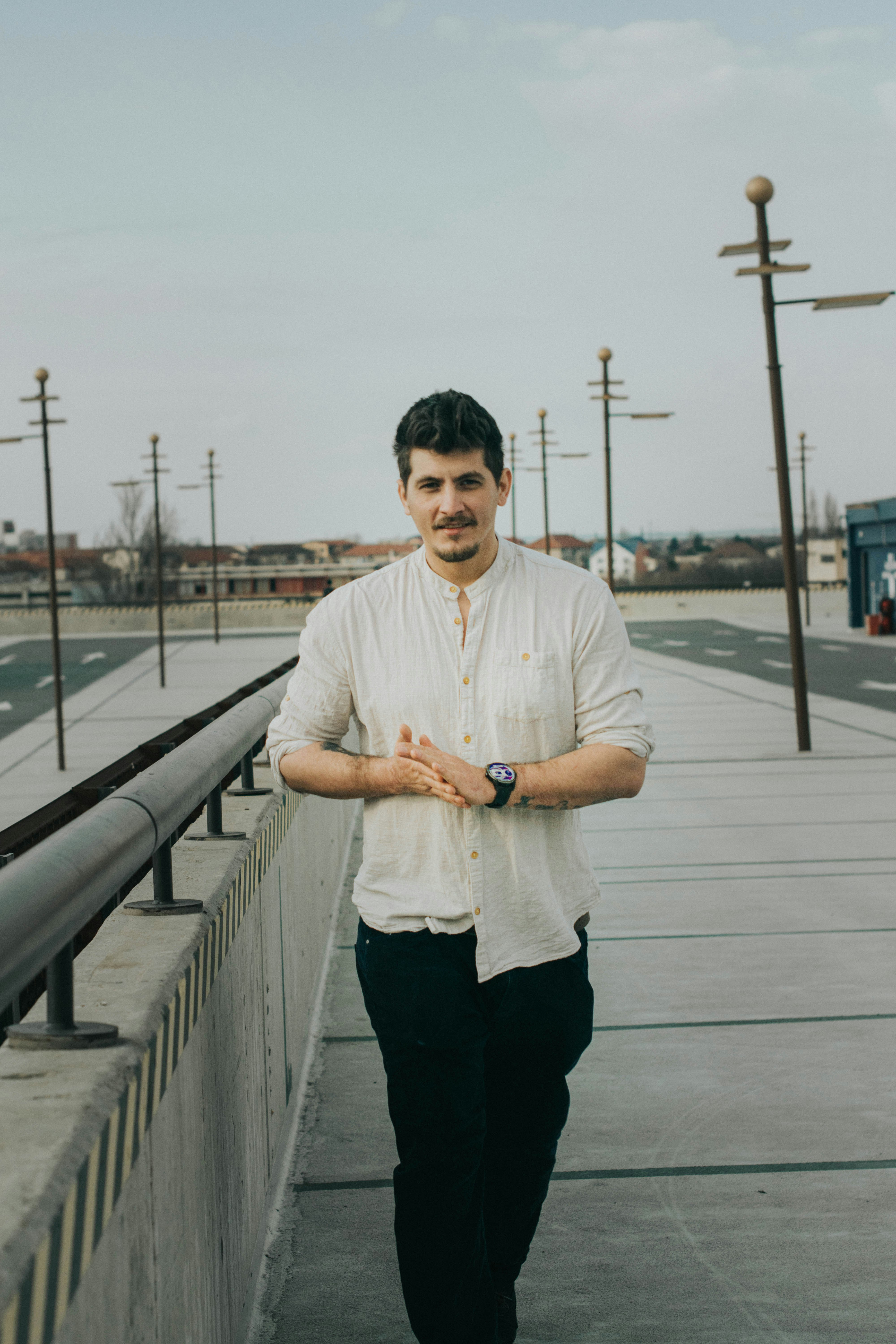 man in white dress shirt and black pants standing on gray concrete pavement during daytime